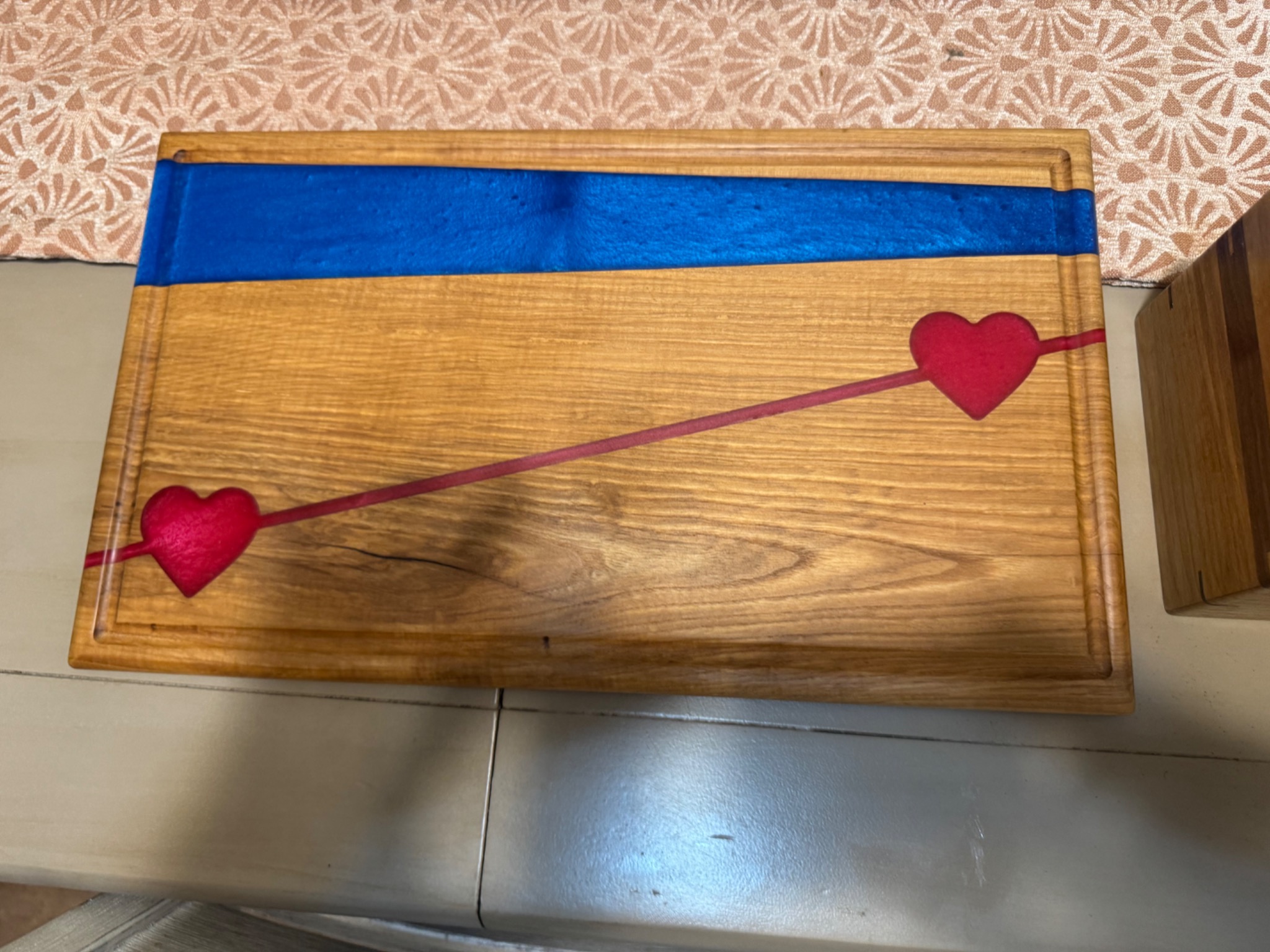 Rectangular wooden charcuterie board with a blue epoxy band and red heart accents